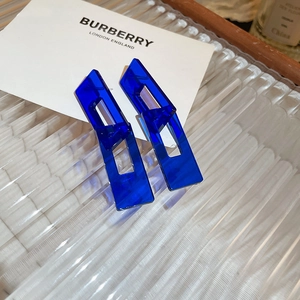 Macro detail of Klein blue geometric hollow acrylic earrings on a frosted glass tray