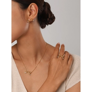 Detail of 18k gold plated stainless steel bow jewelry set worn by a model