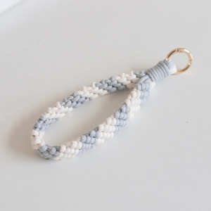 Close-up of handmade gray and white woven cotton wristlet strap with gold metal clasp