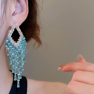 Macro shot of elegant silver needle drop earrings with blue sparkling zircon tassels