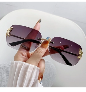 Detailed view of frameless sunglasses with purple gradient lenses and gold butterfly accents
