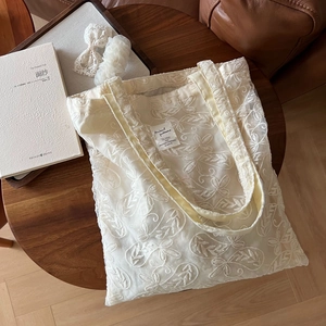 Macro shot of cream lace embroidery details and fabric label on a vintage tote bag