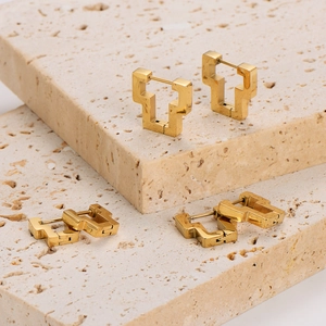 Three pairs of geometric hollow gold earrings displayed on elegant natural stone steps