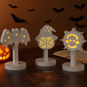 Three Halloween LED lights featuring bat, wizard hat and skull helm on a cozy autumn desk
