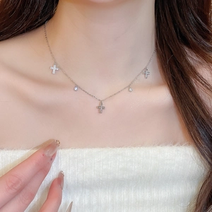 Close-up of elegant silver necklace featuring zircon-encrusted crosses on a model