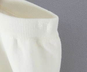 Detaillierte Makroaufnahme der weißen gerippten Strickstruktur an Bund und Ärmel