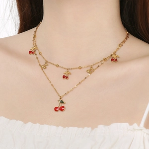 Collier double rang en acier doré avec pendentifs cerises rouges porté par un mannequin