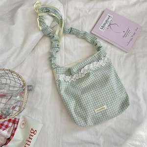 Flat lay of plaid tote bag with white lace trim, yellow ribbon, and ruffled shoulder strap