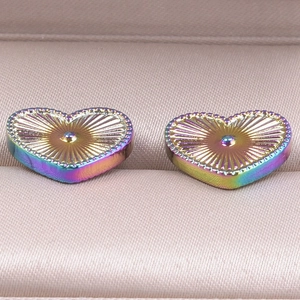Macro shot of rainbow-plated heart studs with radial texture and beaded edges