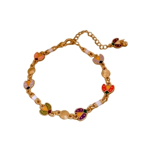 Vintage gold ladybug bracelet with colorful enamel pendants on a clean white background