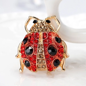 Macro shot of gold-tone ladybug brooch with red rhinestones and black crystal spots