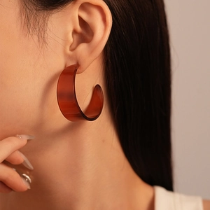 Elegant vintage amber acrylic C-shaped hoop earring worn by a model in warm light