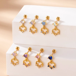 Clous d'oreilles cœur dorés avec pierres précieuses colorées sur support d'exposition