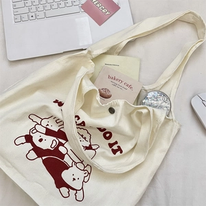 Gros plan d'un sac fourre-tout en toile crème avec bouton pression et motif d'ours