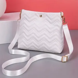 Quilted white crossbody bag with wave chevron pattern and adjustable shoulder strap