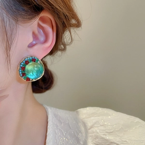 Gros plan de boucles d'oreilles bohèmes vintage avec pierres vert émeraude et détails en métal