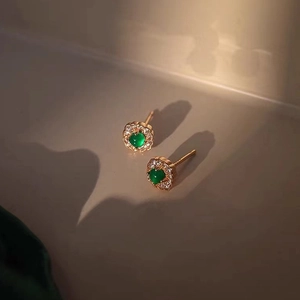 Macro shot of S925 silver round earrings with green gemstone and diamond halo