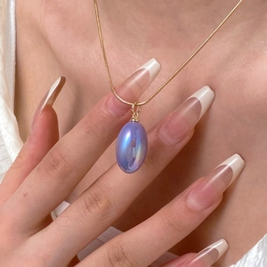 Detailed view of iridescent pear-shaped purple pendant on a sleek gold snake chain necklace