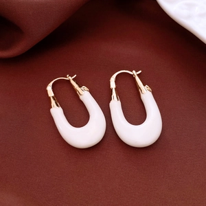 Macro detail of white U-shaped vintage earrings with gold plating on silk fabric