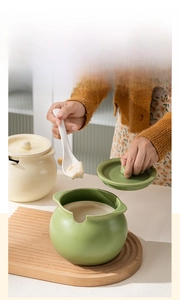 Detail of cream ceramic lard storage jars with lids on a wooden base in a kitchen