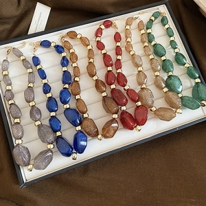 Detail of irregular acrylic beaded necklaces with glitter finish and gold metal spacers