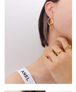 Close-up of gold asymmetrical chain earring and minimalist knot rings on model
