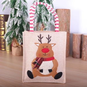 Sac cadeau de Noël en lin avec motif renne et poignées rayées dans un décor festif rouge