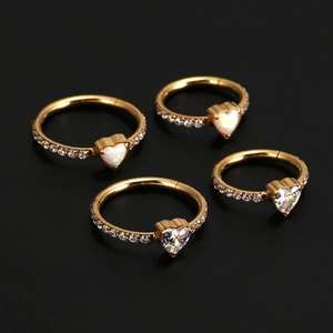 Detailed shot of golden stainless steel heart nose rings with opal and zircon gemstones