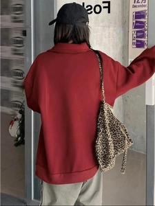 Λεπτομερής όψη του σκούρου κόκκινου oversized φούτερ και ανάγλυφο ύφασμα για το χειμώνα