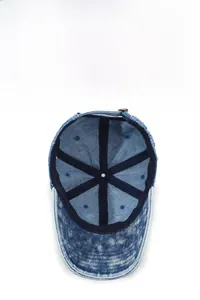 Detail of washed denim baseball cap featuring breathable eyelets and metal adjustment buckle
