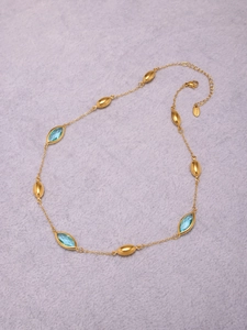 Close-up of gold stainless steel necklace with blue marquise gems and lobster clasp detail