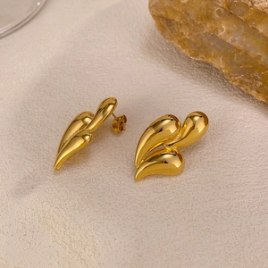 Detailed view of gold plated stainless steel teardrop earrings on a textured stone background