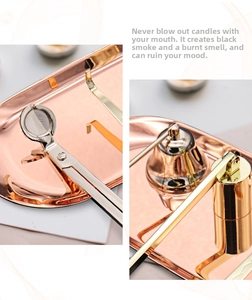 Detail view of rose gold stainless steel candle wick trimmer and snuffer set on tray