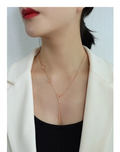 Close-up of rose gold Y-shaped necklace with LOVE lettering and vertical bar pendant
