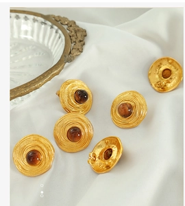 Detailed macro view of vintage gold stud earrings with tiger eye stone on white fabric