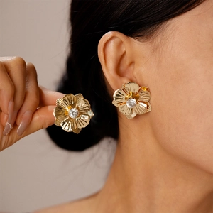 Gros plan de boucles d'oreilles fleur dorée avec strass étincelant portées par un mannequin