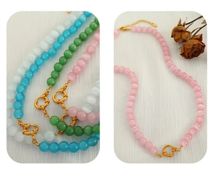 Detail of colorful faceted cat eye stone beaded necklace with a bright gold metal clasp