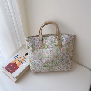 Vue détaillée du sac cabas en coton fleuri avec anses en cuir beige et rivets en métal