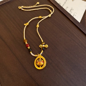 Ethnic gold pendant necklace with pearl weaving rope and colorful charm on wooden tray