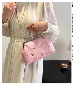 Detail of pink floral embroidery and vintage metal clasp on a stylish handbag with chain