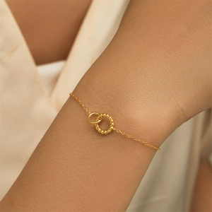 Close-up of golden intertwined rings with twisted rope texture on a delicate chain