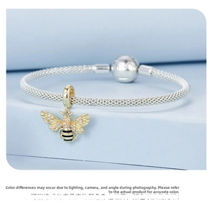 Macro view of a gold bee charm with crystal wings on an S925 silver braided bracelet
