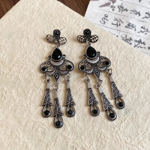 Macro shot of vintage silver earrings featuring intricate filigree and black teardrop stones