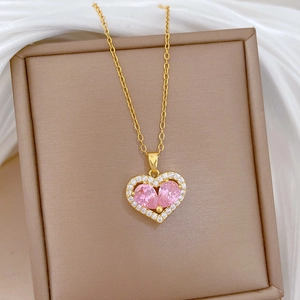 Macro shot of gold heart necklace with pink gemstone and crystals on jewelry box