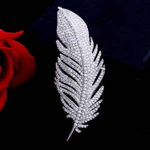 Macro shot of silver feather brooch with sparkling zircons on a dark textured surface