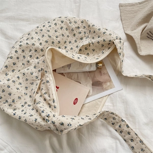 Detail view of floral canvas tote bag showing zipper closure and spacious interior items