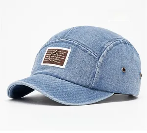 Close-up of a blue washed denim 5-panel baseball cap with a brown leather patch
