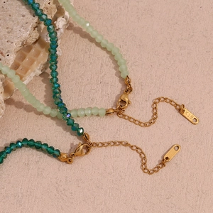Detailed macro view of 18K gold-plated lobster clasp and green faceted crystal beads