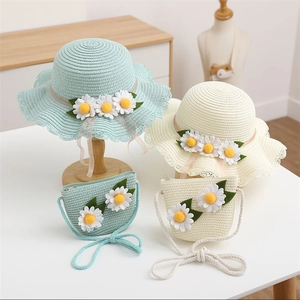 Detail of hand-woven straw hat and matching bag set with white daisy flower accents