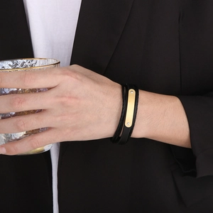 Primo piano di un bracciale multistrato in pelle nera da uomo con placca in oro lucido
